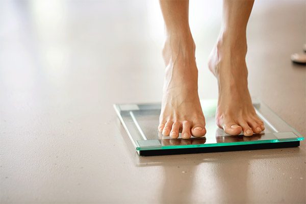Ernährungstherapie und Gewichtsverlust: Füße auf Waage