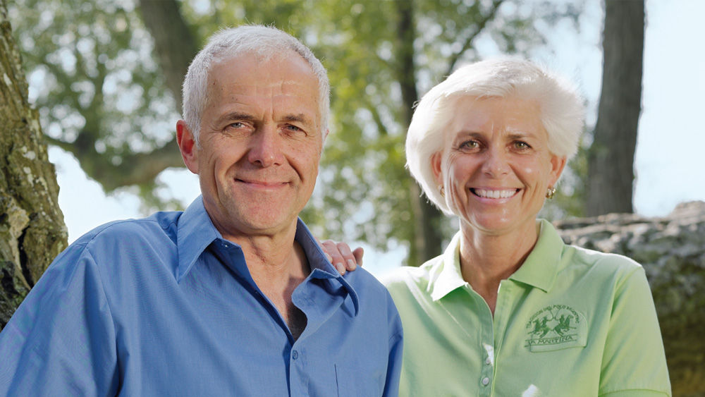 Ein mittelalterlicher Mann und eine Frau sitzen lächelnd zusammen im Wald