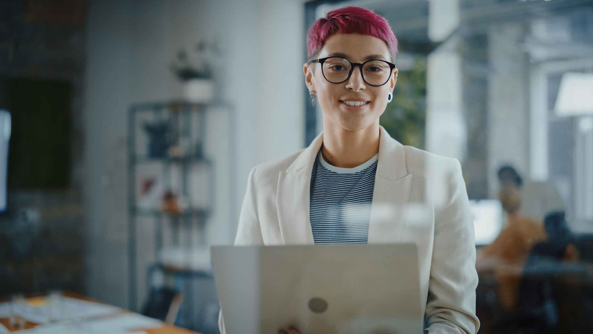 Modern Office: Portrait of Beautiful Creative Specialist with Short Pink Hair Standing, Holding Laptop Computer. Working on App Design, Data Analysis, Plan Strategy for Social Media Disruption, Modern Office: Portrait of Beautiful Creative Specialist with Sh