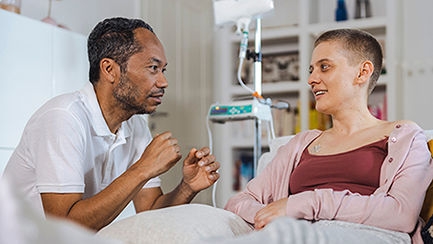 Das Bild zeigt einen Pfleger und eine Patientin, die parenteral ernährt wird