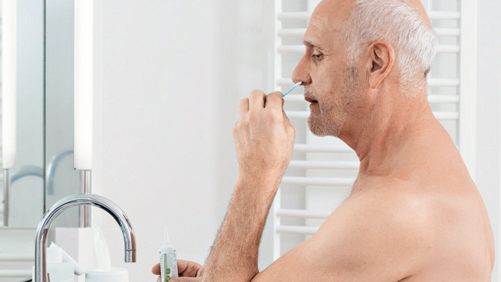 älterer Mann spült antimikrobielle Nase zu Hause vor dem Badespiegel 