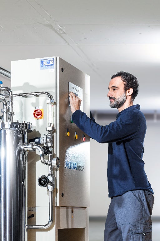 Ein Mann drückt eine Taste am Gerät „AquaBoss“