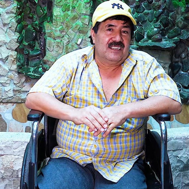 Mann aus Ecuador mit Mütze sitzt im Rollstuhl