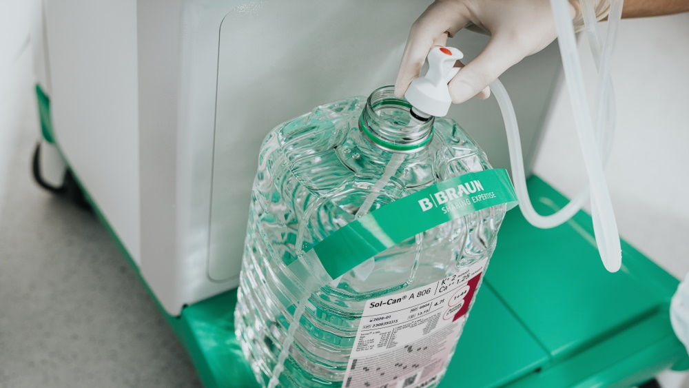 Die Hand einer medizinischen Fachkraft, die den Saugstab in einen Sol-Can-A Kanister hält, um die Flüssigkeit zu entnehmen