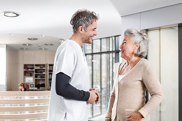 Ein Pfleger befindet sich im Gespräch mit einer Patientin.