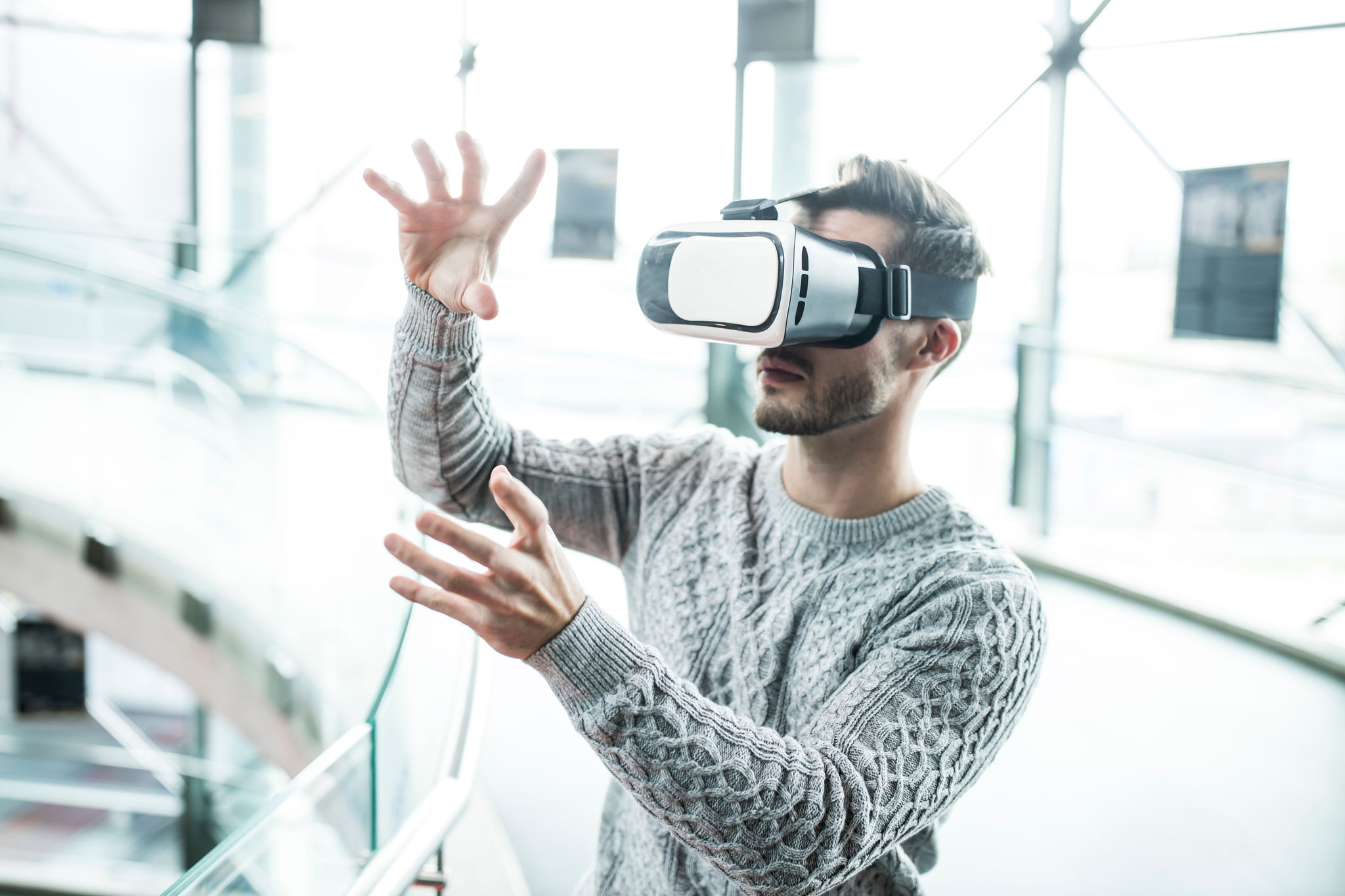 Tech developer with virtual reality headset gesturing at robotic workshop