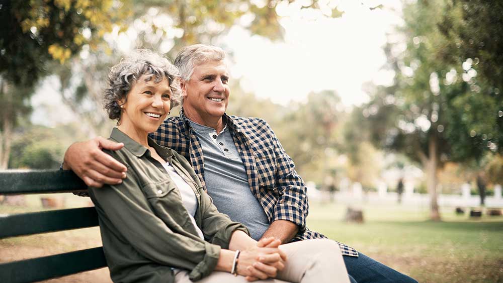 Paar sitzt auf einer Bank und er legt seine Hand auf ihre Schulter