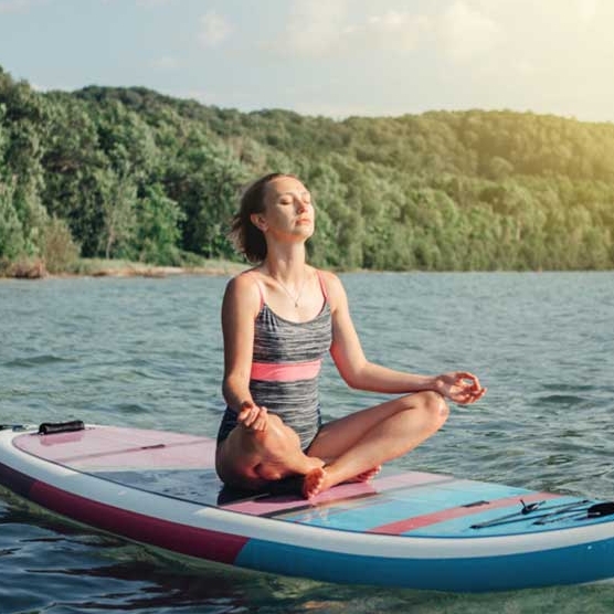 Eine junge Frau meditiert auf einem Stand-up-Paddleboard