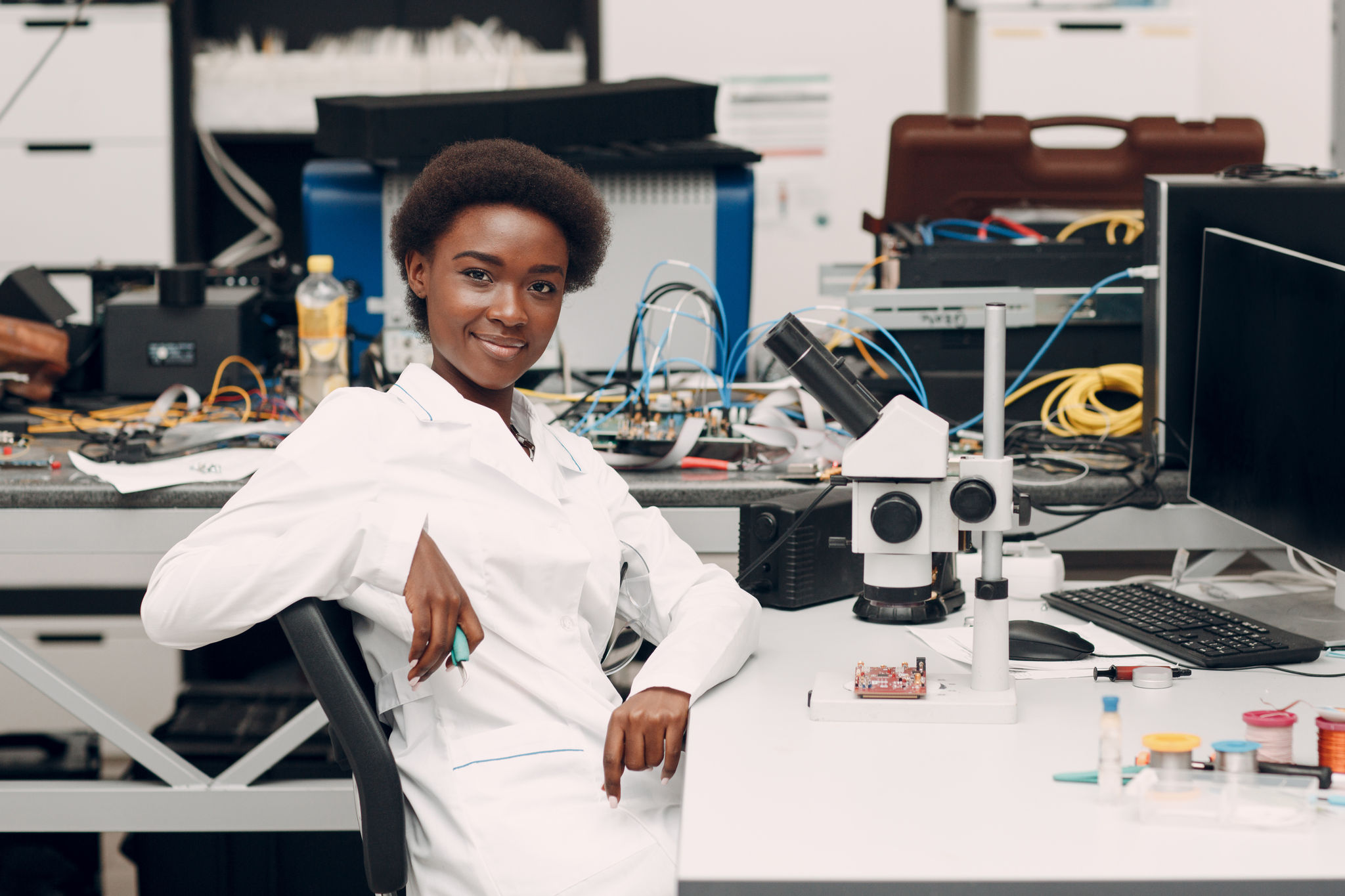 Scientist african american woman engineer working in laboratory with electronic tech instruments and microscope. Research and development of electronic devices by color black woman.