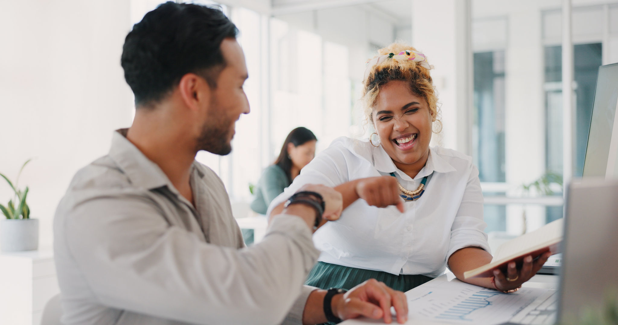 Laptop, success or happy employees fist bump in celebration of sales goals or target at office desk. Support, mission or woman celebrates partnership growth, team work or achievement with worker.