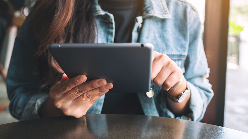Closeup image of a woman holding and using tablet pc while sitting in cafe, Closeup image of a woman holding and using tablet pc while sitti