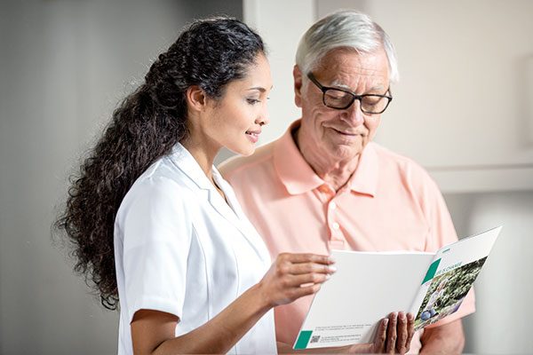 Ärztin und Patient blicken gemeinsam in eine Broschüre zur Heimdialyse.