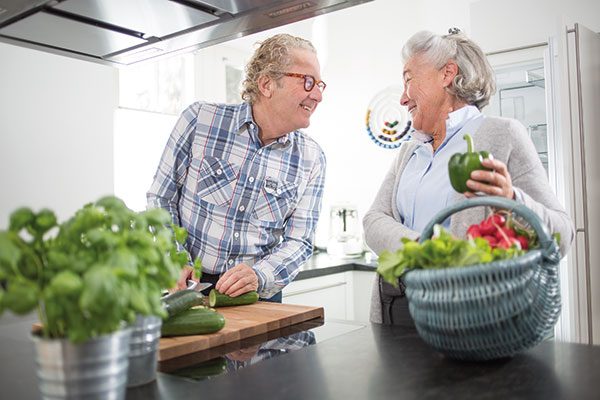 Ein Ehepaar verarbeitet verschiedene Gemüsesorten in der Küche.