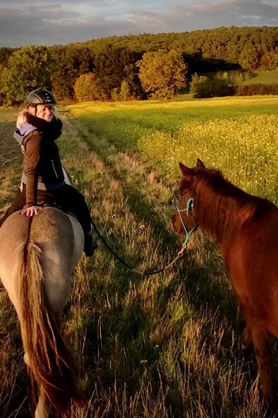 Julia Bangert sitzt auf ihrem Pferd, während sie sich umdreht und in die Kamera lächelt.