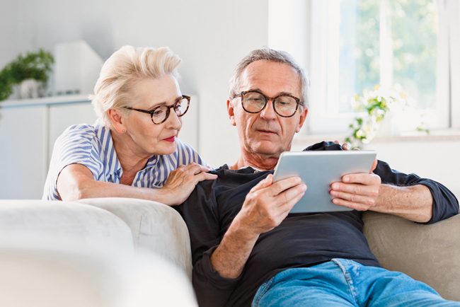 Ein Ehepaar schaut gemeinsam auf ein Tablet und informiert sich über den Wechsel des Homecare-Versorgers. 