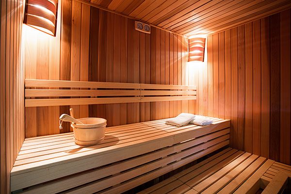 Eine stimmungsvoll beleuchtete Sauna, die mit Holzbänken ausgestattet ist. 