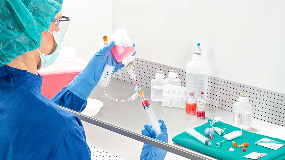 Apothekerin zieht Spritze unter Laminaluftstrom