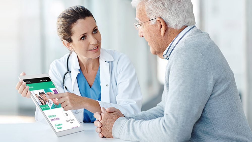 Ein Arzt und ein Patient sitzen zusammen am Tisch. Der Arzt zeigt ihm die ForPatientApp auf einem Tablet.
