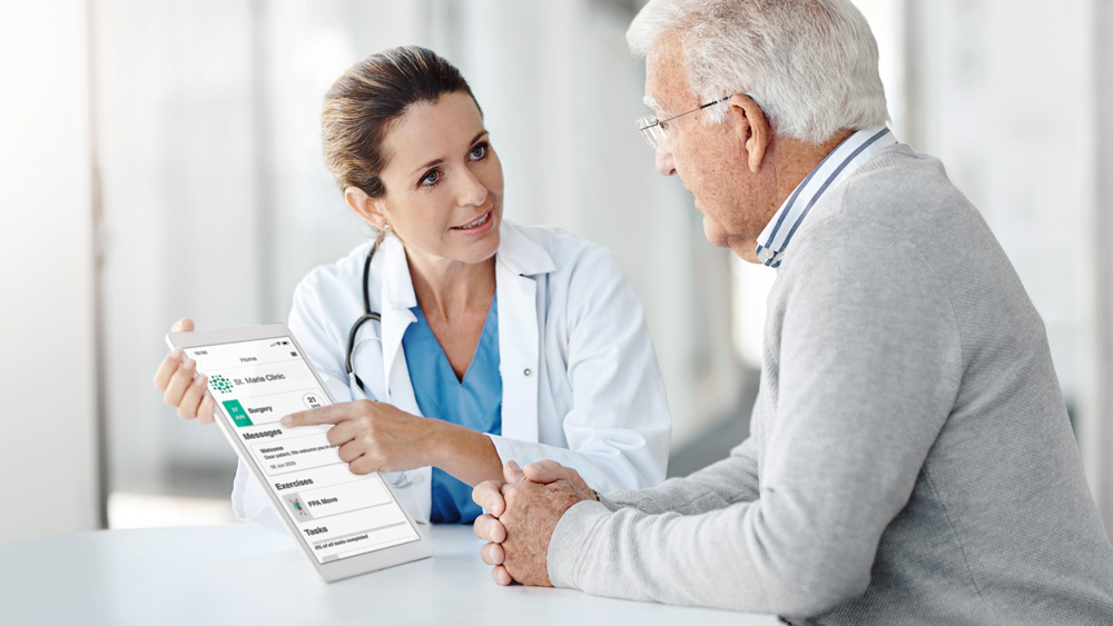 Eine medizinische Fachkraft zeigt einer mittelalterlichen Patientin die ForPatientApp und erklärt die Funktionen der App