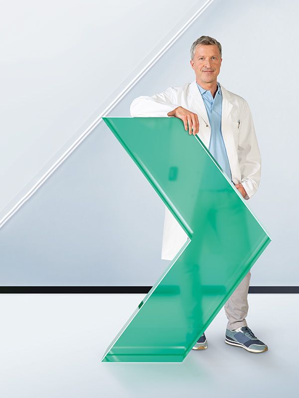 Ein männliches medizinisches Fachpersonal hält ein grünes Schild, das einen Weg zeigt