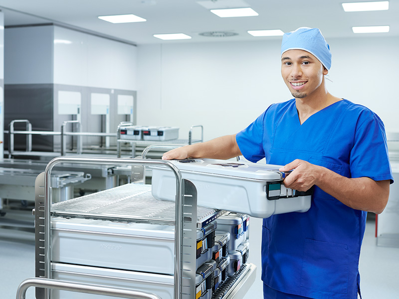 Ein männliches medizinisches Fachpersonal hält lächelnd einen riesigen Behälter