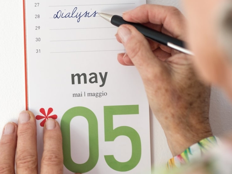 Eine Hand schreibt mit einem Kugelschreiber Dialyse in einen Kalender für den 28. Mai