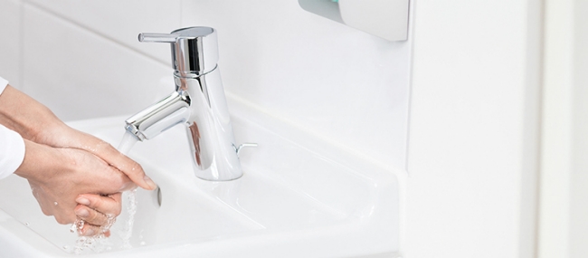 Healthcare professional cleans hands with soap and water.